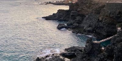 brown rocky mountain beside body of water during daytime