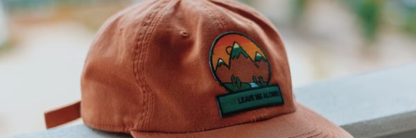 orange and green mountain embroidered cap on pavement